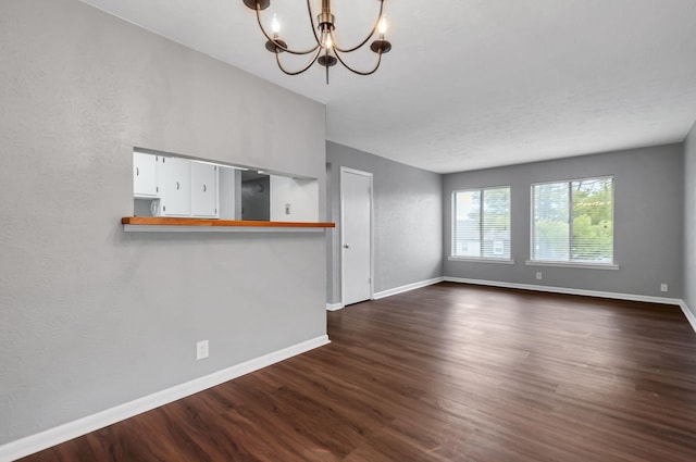 unfurnished living room featuring dark hardwood / wood-style floors and an inviting chandelier