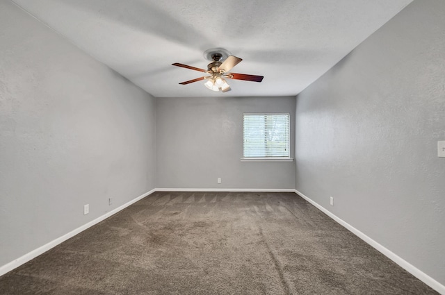 unfurnished room with ceiling fan, dark carpet, and a textured ceiling