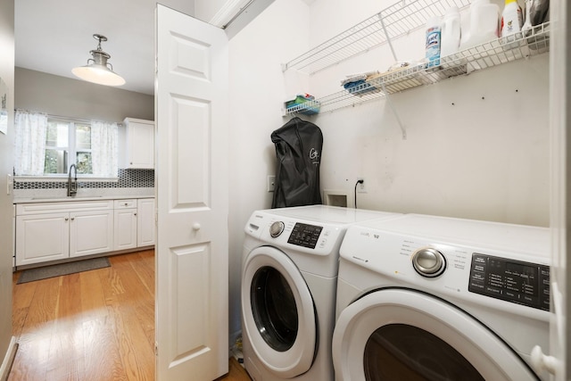 laundry area featuring washing machine and clothes dryer, light wood-type flooring, and sink