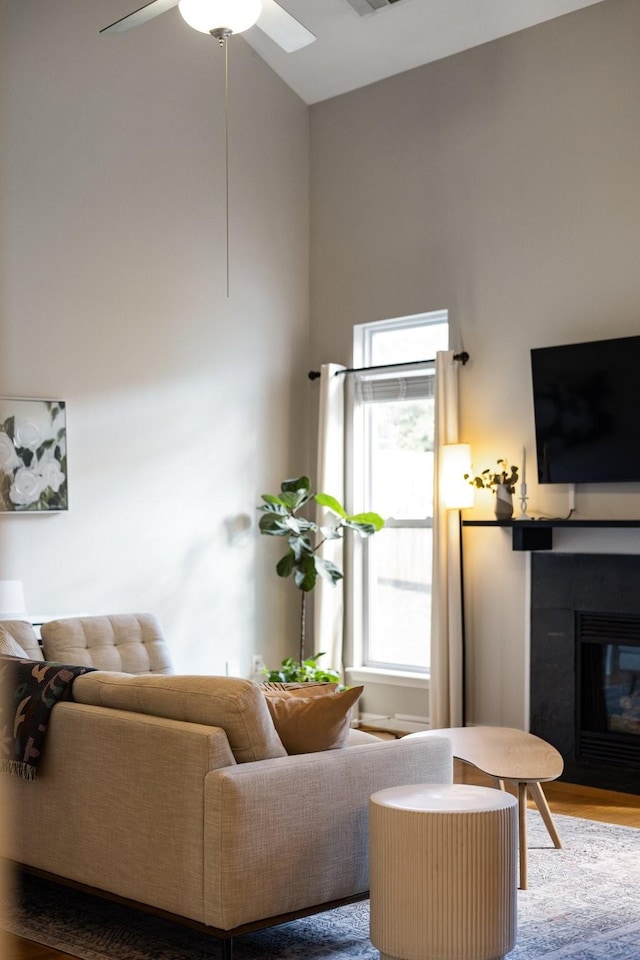 living room featuring a fireplace, wood-type flooring, and ceiling fan