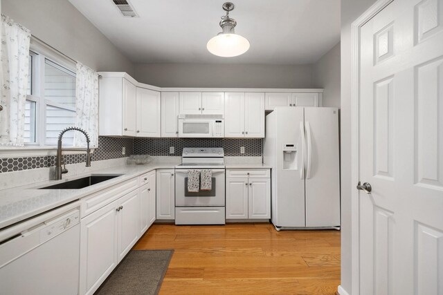 kitchen featuring sink, backsplash, decorative light fixtures, white appliances, and white cabinets