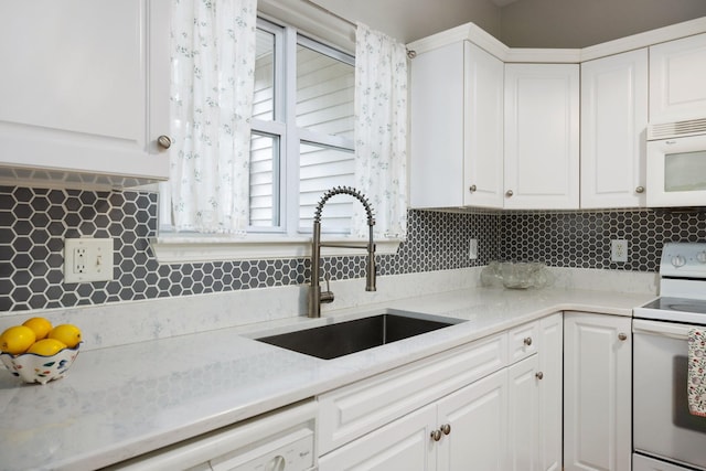 kitchen with white appliances, white cabinetry, and sink