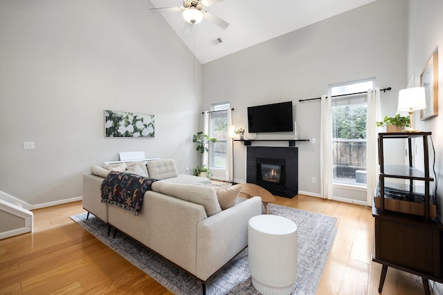 living room with light wood-type flooring, high vaulted ceiling, and ceiling fan