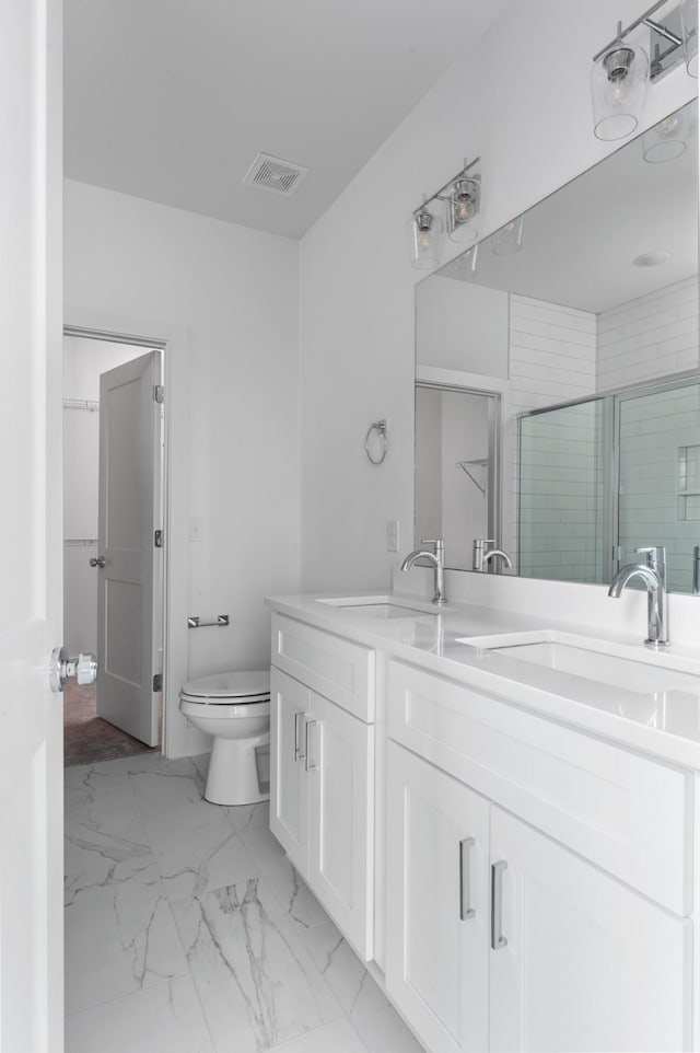 bathroom featuring a shower with shower door, vanity, and toilet