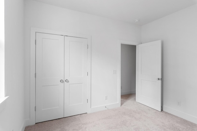 unfurnished bedroom featuring light carpet and a closet