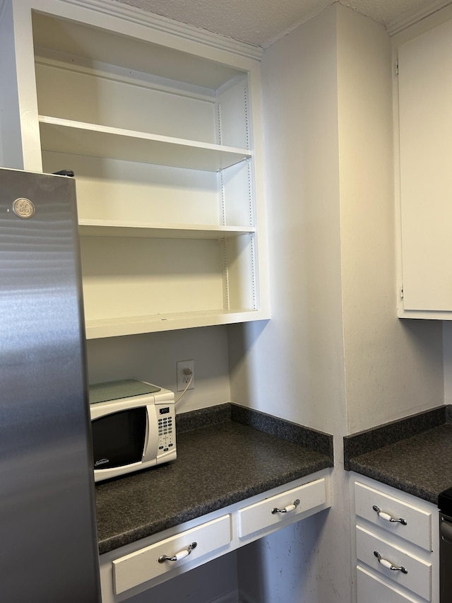 kitchen featuring white cabinets and stainless steel refrigerator