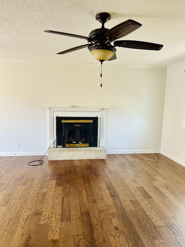 unfurnished living room with baseboards, ceiling fan, a fireplace, wood finished floors, and a textured ceiling