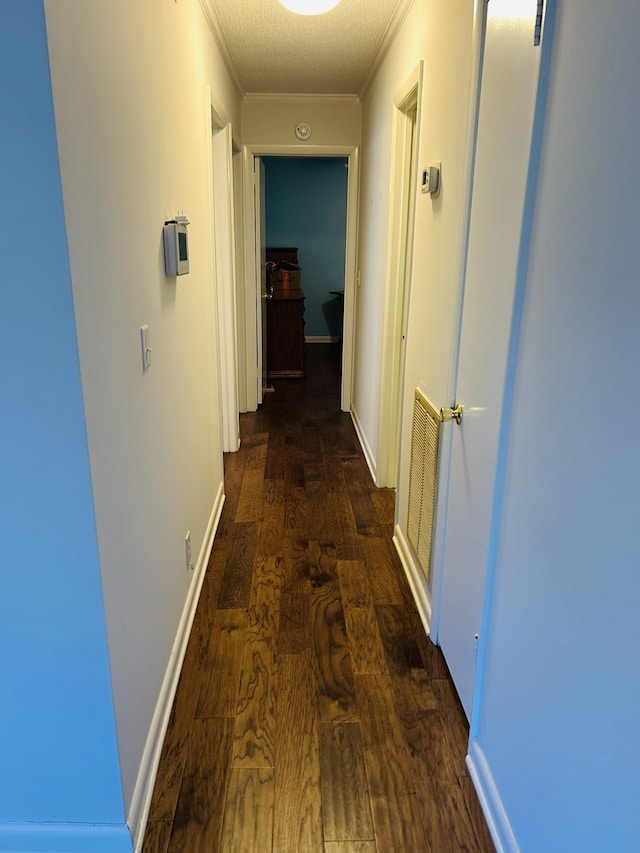 hall featuring crown molding, dark wood-type flooring, and a textured ceiling