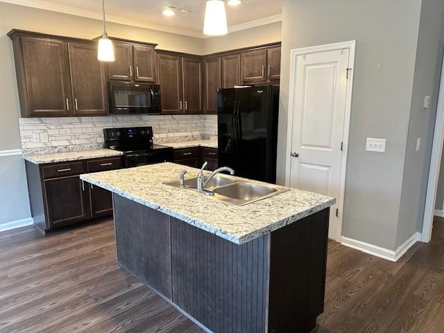 kitchen featuring pendant lighting, black appliances, sink, dark hardwood / wood-style floors, and an island with sink