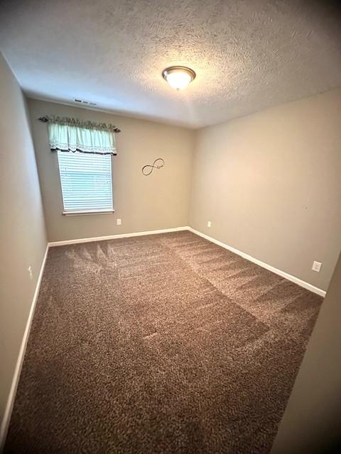 carpeted empty room featuring a textured ceiling