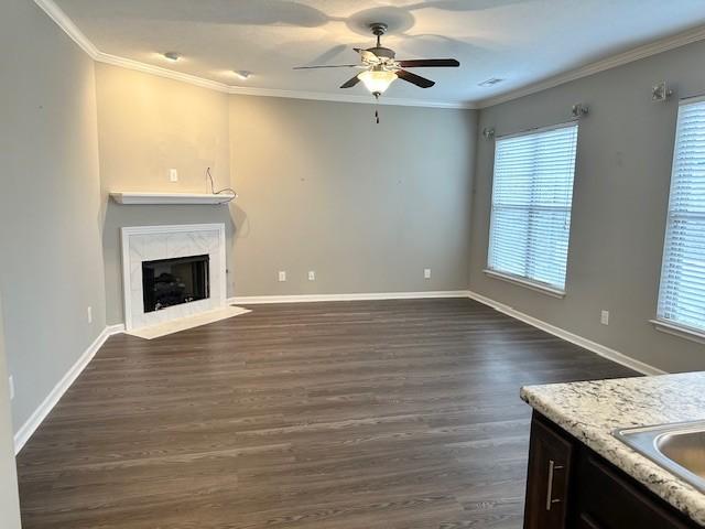 unfurnished living room featuring ceiling fan, dark hardwood / wood-style flooring, crown molding, and a tile fireplace