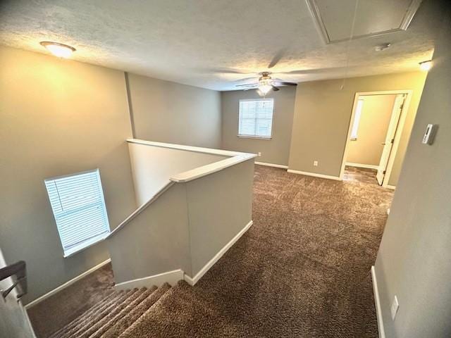 corridor featuring dark colored carpet and a textured ceiling