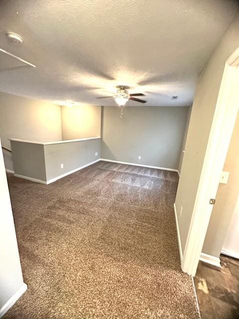 unfurnished room featuring a textured ceiling, dark carpet, and ceiling fan