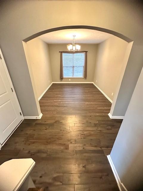 unfurnished dining area with dark hardwood / wood-style floors and a chandelier