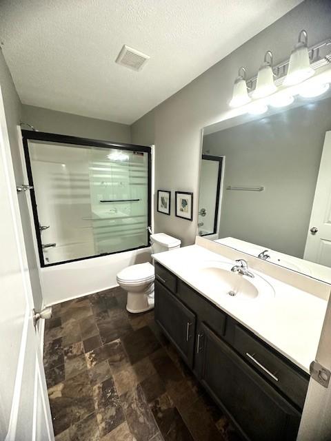 full bathroom with vanity, toilet, shower / bath combination with glass door, and a textured ceiling