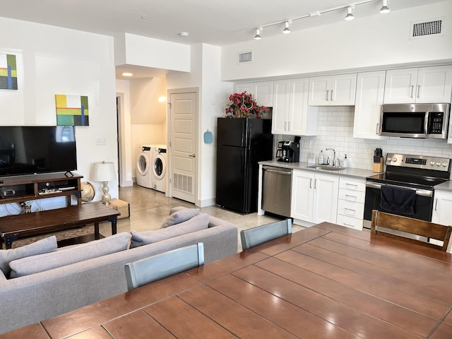 kitchen featuring washing machine and dryer, sink, white cabinets, and appliances with stainless steel finishes