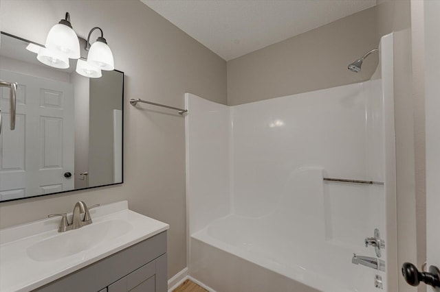 bathroom with a textured ceiling, vanity, and tub / shower combination