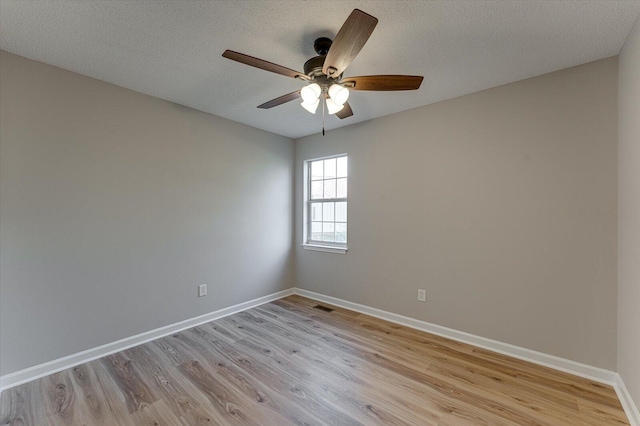 empty room with ceiling fan, a textured ceiling, and light wood-type flooring