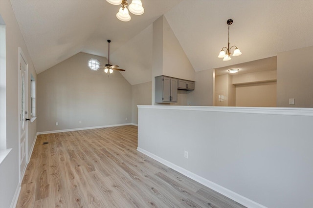 interior space featuring vaulted ceiling, ceiling fan with notable chandelier, and light wood-type flooring