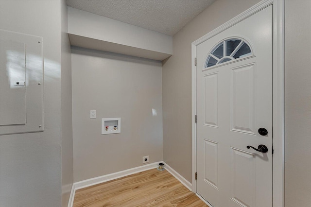 washroom featuring electric panel, washer hookup, a textured ceiling, hookup for an electric dryer, and light hardwood / wood-style floors