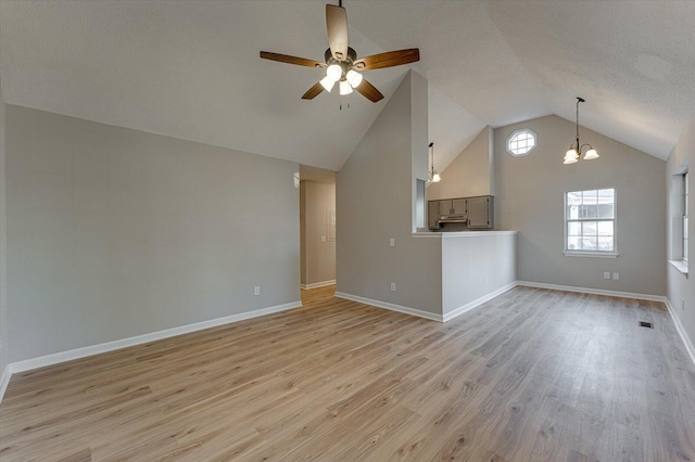 unfurnished living room featuring ceiling fan with notable chandelier, lofted ceiling, a textured ceiling, and light hardwood / wood-style flooring