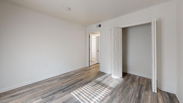 unfurnished bedroom with dark hardwood / wood-style flooring and a closet