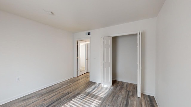 unfurnished bedroom with a closet and dark wood-type flooring