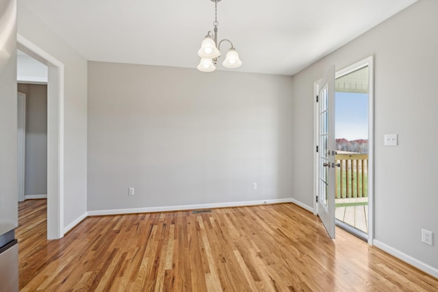 empty room with light hardwood / wood-style flooring and a notable chandelier