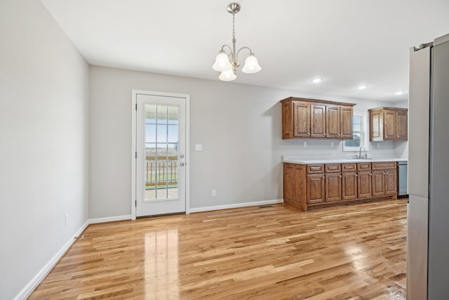 kitchen with dishwasher, sink, light wood-type flooring, decorative light fixtures, and a chandelier