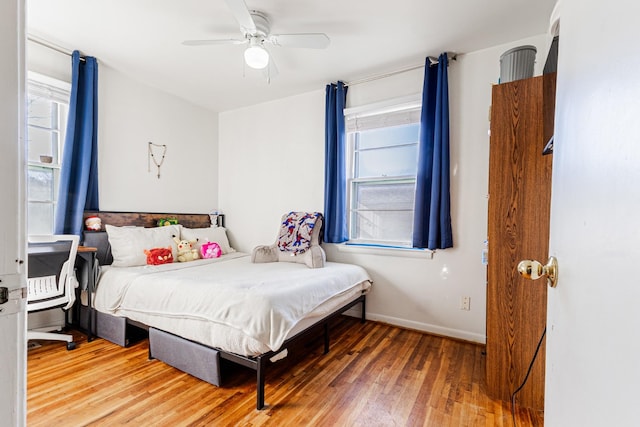 bedroom with multiple windows, hardwood / wood-style floors, and ceiling fan