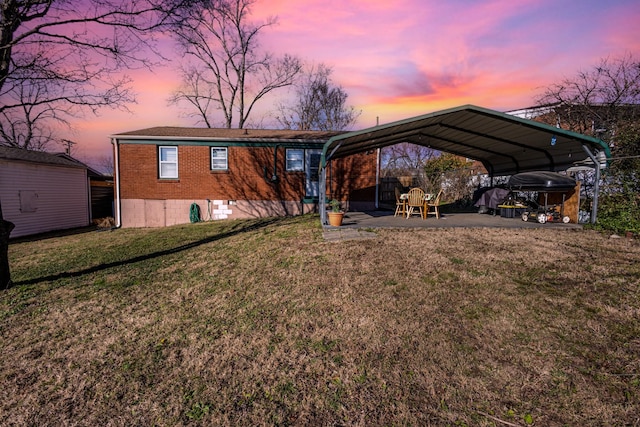 back house at dusk with a yard and a carport