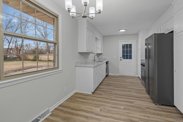 kitchen with sink, a textured ceiling, stainless steel appliances, and white cabinets