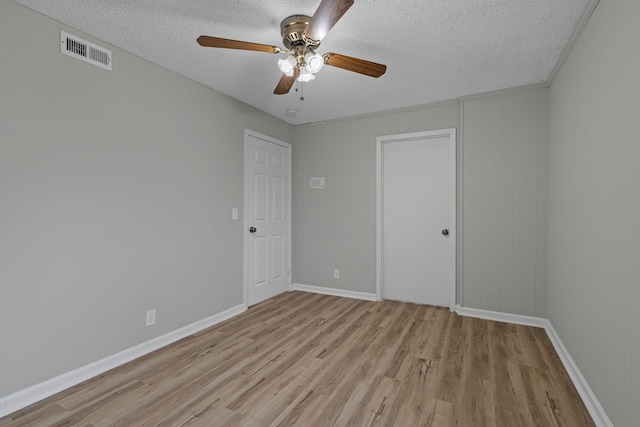 unfurnished room with ceiling fan, a textured ceiling, and light wood-type flooring