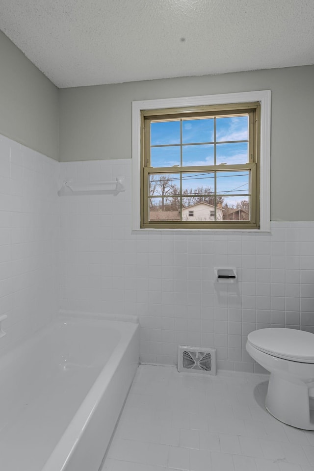 bathroom with tile patterned flooring, tile walls, and a textured ceiling