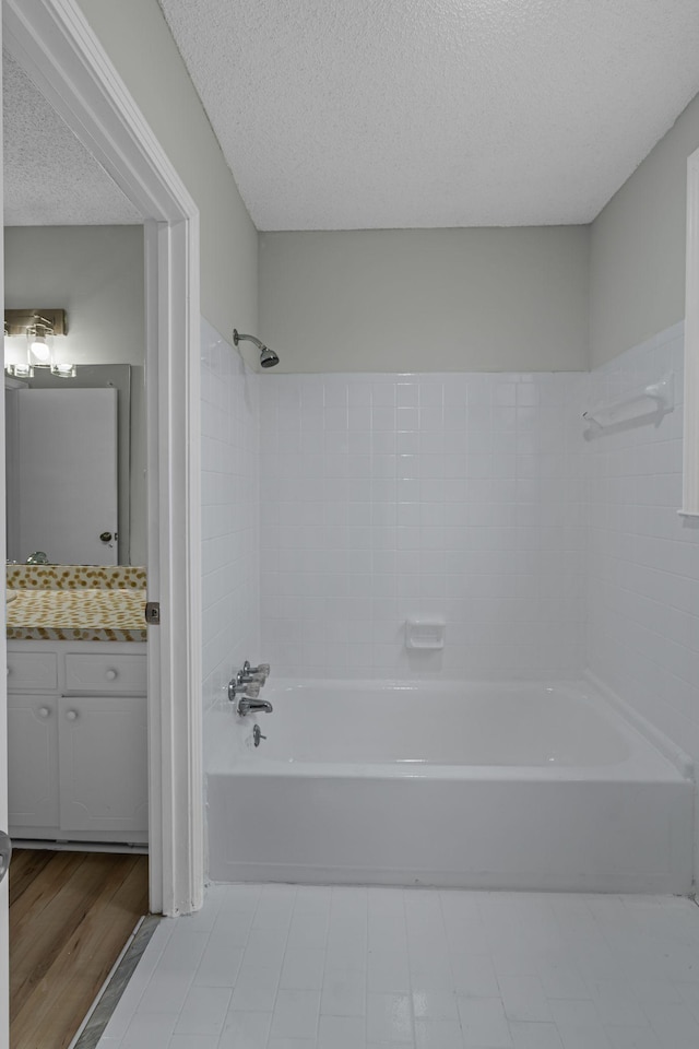 bathroom with vanity, tiled shower / bath combo, and a textured ceiling