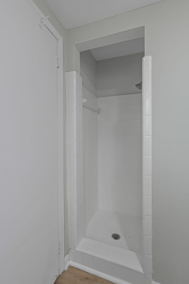 bathroom featuring wood-type flooring and tiled shower