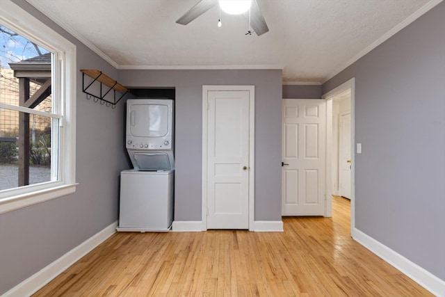 washroom with stacked washer and dryer, ornamental molding, plenty of natural light, and light wood-type flooring