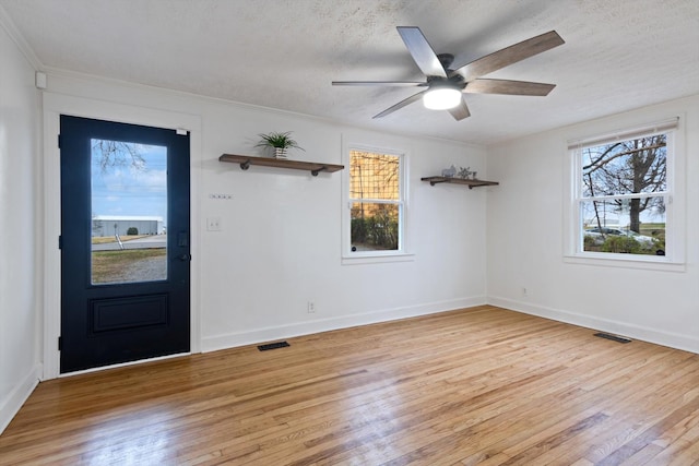 foyer entrance with a textured ceiling, ceiling fan, and light hardwood / wood-style flooring