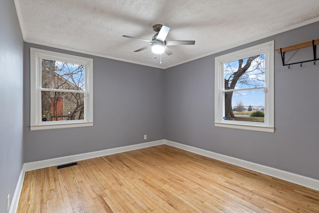 empty room with a textured ceiling, ceiling fan, light hardwood / wood-style flooring, and a healthy amount of sunlight