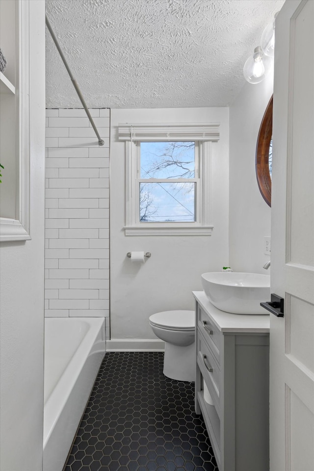 full bathroom with toilet, tiled shower / bath combo, a textured ceiling, and vanity