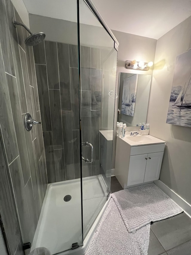 bathroom featuring a stall shower, tile patterned floors, baseboards, and vanity