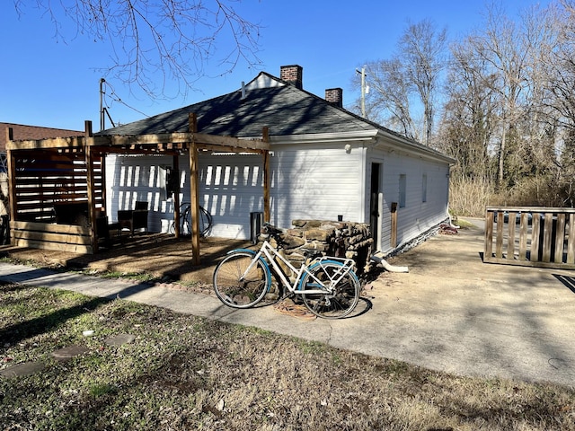 view of side of property featuring a chimney and a pergola