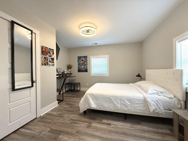 bedroom featuring multiple windows, wood finished floors, visible vents, and baseboards