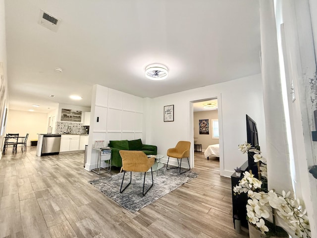 living area with light wood-type flooring, visible vents, and baseboards