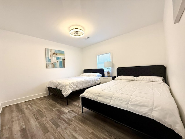 bedroom featuring visible vents, baseboards, and wood finished floors