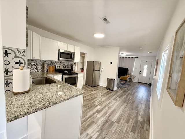 kitchen with visible vents, light wood-style flooring, stainless steel appliances, white cabinetry, and a sink