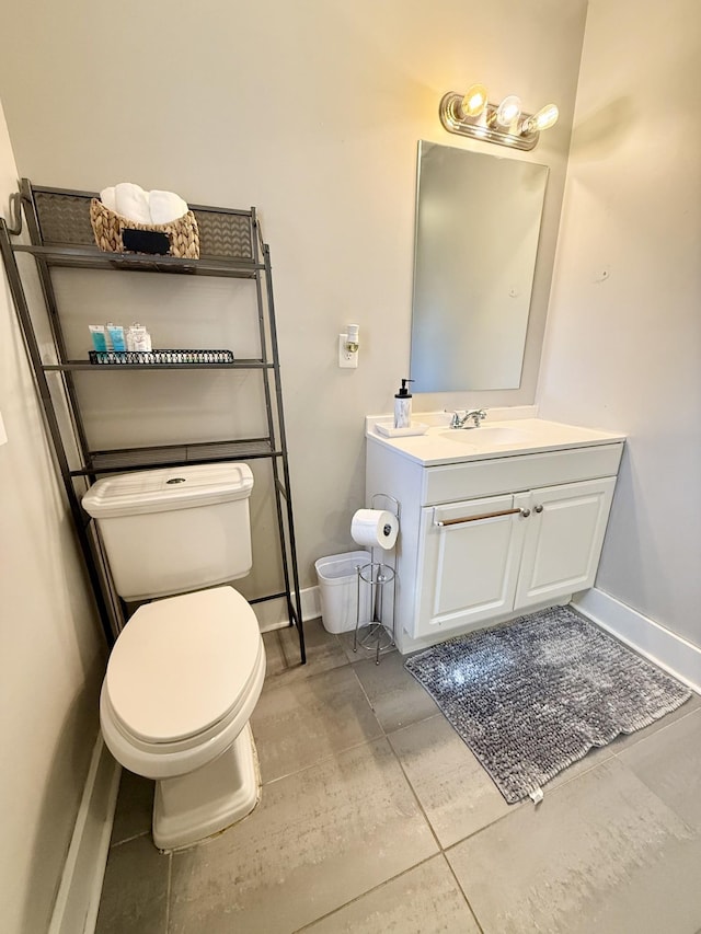 half bath with vanity, toilet, and baseboards