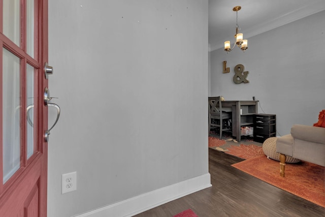 entryway with crown molding, dark wood-type flooring, and a notable chandelier