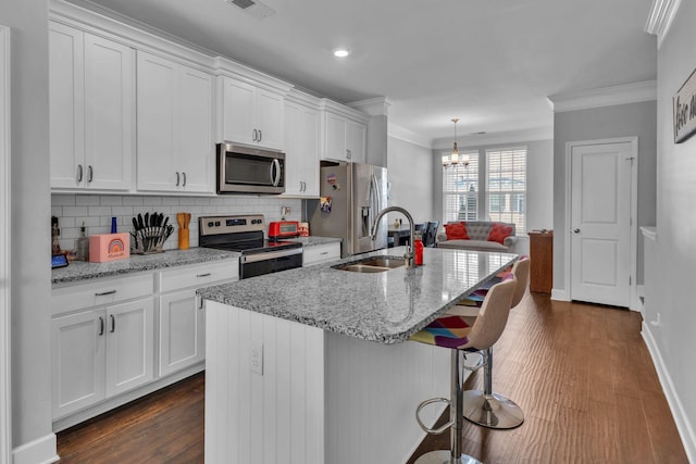 kitchen with a kitchen island with sink, white cabinets, sink, appliances with stainless steel finishes, and tasteful backsplash