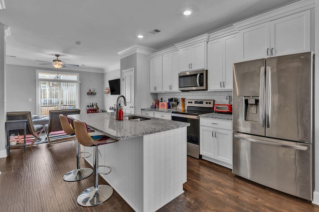 kitchen with white cabinets, appliances with stainless steel finishes, sink, and an island with sink